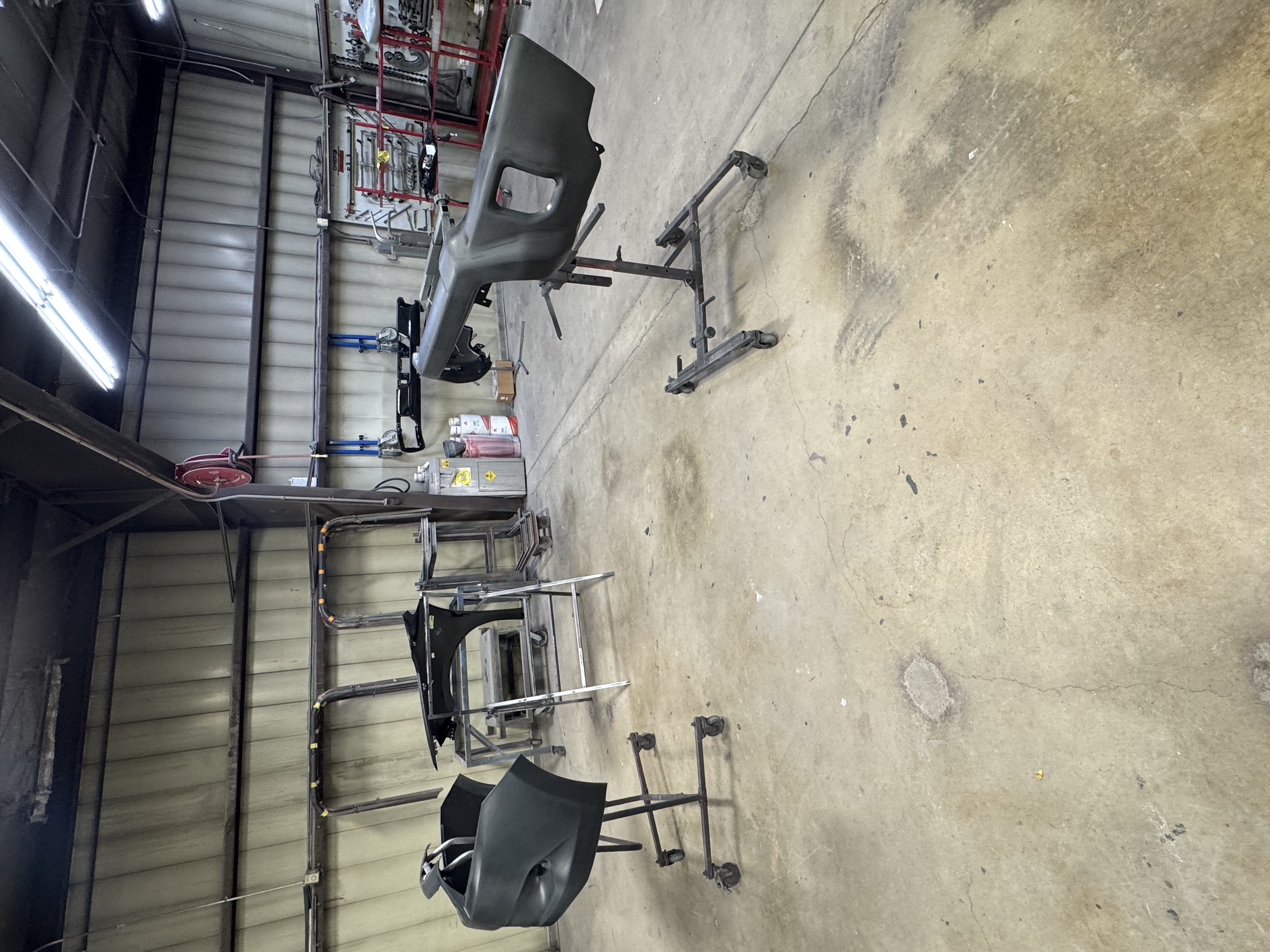 Vehicle bumper parts on rolling stands inside the repair shop