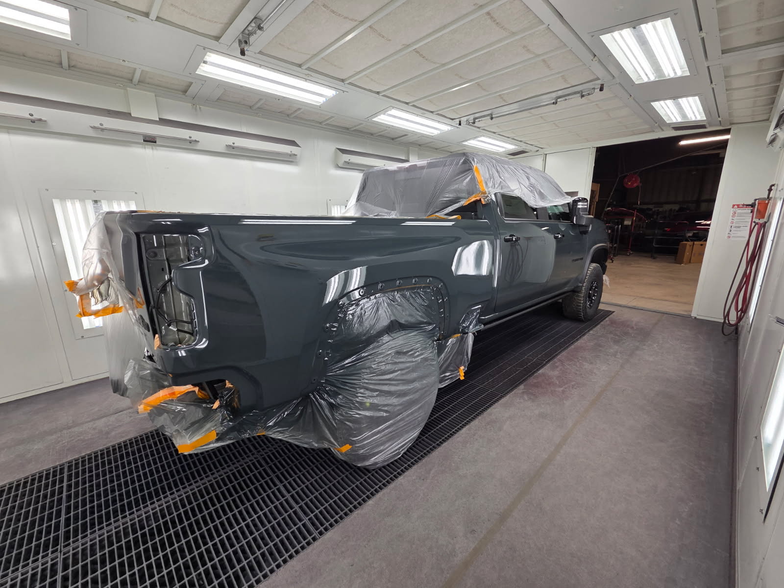 Charcoal-gray pickup masked in plastic and ready for paint in the booth